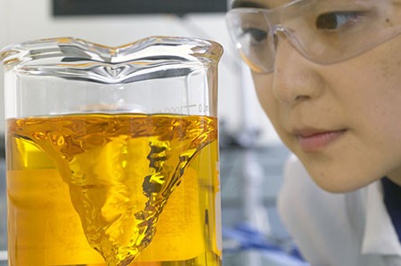 科万斯的一位科学家在研究一个烧杯，在开发的先导优化阶段测试药物。